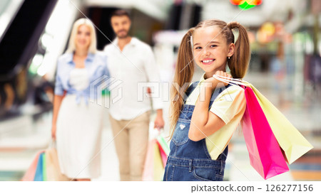 Family Shopping. Happy Girl Holding Shopper Bags Spending Time With Parents In Mall. Selective Focus Family Shopping. Happy Girl Holding Shopper Bags Spending Time With Parents In Mall. Selective Focus 126277156