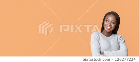 Beautiful black lady looking with interest at copy space over beige background, attracted with exciting info, panorama 126277224