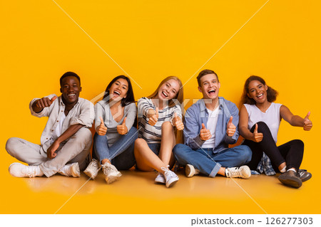 Positive group of international students showing thumbs up over yellow background, enjoying life 126277303