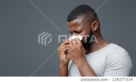 Afro man touching his nose with napkin, having runny nose, got flue, free space Afro man touching his nose with napkin, having runny nose, got flue, free space 126277334
