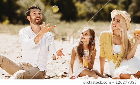 After-Quarantine Summer Picnic. Cheerful Family Enjoying Sunny Day In Nature Sitting On Blanket Outdoors Having Fun Juggling With Fruits After-Quarantine Summer Picnic. Cheerful Family Enjoying Sunny Day In Nature Sitting On Blanket Outdoors Having Fun Juggling With Fruits 126277355