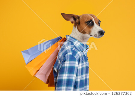 A dog wearing a blue plaid shirt stands against a yellow background, looking to the right. The dog is holding four shopping bags in its mouth, two blue, one orange, and one pink. A dog wearing a blue plaid shirt stands against a yellow background, looking to the right. The dog is holding four shopping bags in its mouth, two blue, one orange, and one pink. 126277362