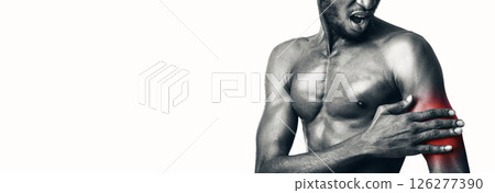 Sports Injuries. Professional Sportsman Touching Aching Bicep Muscle On Hand Standing Over White Studio Background. Cropped, Black-And-White Sports Injuries. Professional Sportsman Touching Aching Bicep Muscle On Hand Standing Over White Studio Background. Cropped, Black-And-White 126277390