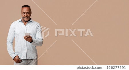 Life online. Modern mature african man chatting on cellphone, orange studio background Life online. Modern mature african man chatting on cellphone, orange studio background 126277391
