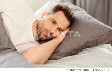 Male Depression Concept. Apathetic Man Having Insomnia Thinking About Problems Lying In Bed At Home. Copy Space Male Depression Concept. Apathetic Man Having Insomnia Thinking About Problems Lying In Bed At Home. Copy Space 126277394