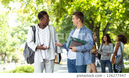 Two international students guys having conversation at public park, having break while studying Two international students guys having conversation at public park, having break while studying 126277447
