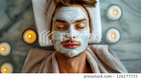 A serene man enjoys a pampering facial treatment surrounded by lit candles. A serene man enjoys a pampering facial treatment surrounded by lit candles. 126277735