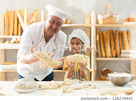 Little daughter and father make dough together in bakery kitchen 126278442