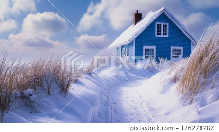 A charming blue house stands alone amidst freshly fallen snow, with tall grass peeking through. The sky is filled with fluffy clouds, creating a serene atmosphere on this beautiful winter day. 126278787