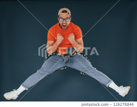 Jumping, feeling good, excited. Handsome man is in the studio against blue background 126278846
