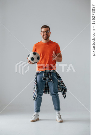 Standing and holding soccer ball. Handsome man is in the studio against white background Standing and holding soccer ball. Handsome man is in the studio against white background 126278857