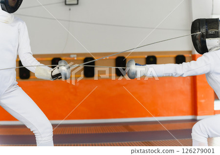 Close-up of fencing swords crossing during intense match indoors Close-up of fencing swords crossing during intense match indoors 126279001