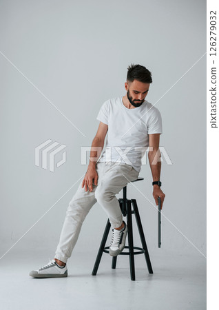 On the chair with laptop. Handsome man is in the studio against white background On the chair with laptop. Handsome man is in the studio against white background 126279032