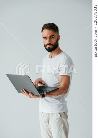 Silver colored laptop in hands. Handsome man is in the studio against white background 126279035