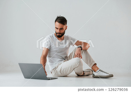 Silver colored laptop in hands. Handsome man is in the studio against white background 126279036