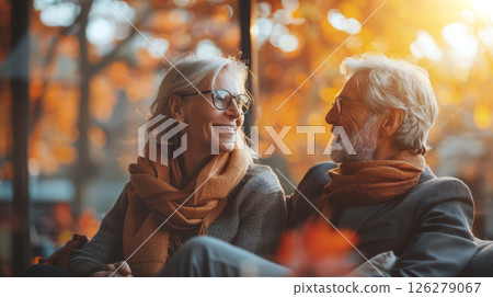 A senior couple smiles at each other, sitting in a cafe during the fall season. 126279067