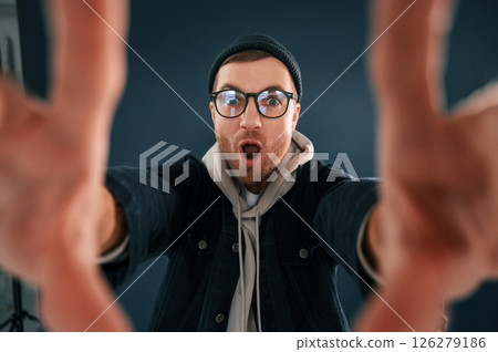 Making the photo by hands, pretending. Smiling. Handsome man is in the studio against blue background Making the photo by hands, pretending. Smiling. Handsome man is in the studio against blue background 126279186