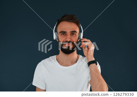 In headphones. Handsome man is in the studio against blue background In headphones. Handsome man is in the studio against blue background 126279330