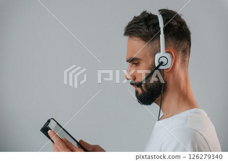 Side view. In headset. Handsome man is in the studio against white background Side view. In headset. Handsome man is in the studio against white background 126279340