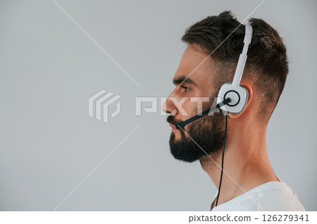 Side view. In headset. Handsome man is in the studio against white background 126279341