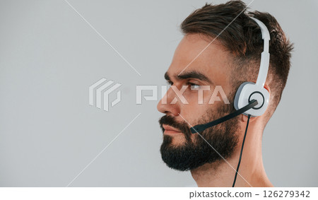 Side view. In headset. Handsome man is in the studio against white background Side view. In headset. Handsome man is in the studio against white background 126279342