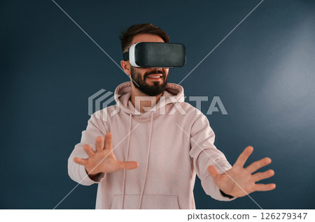 In VR glasses. Handsome man is in the studio against blue background In VR glasses. Handsome man is in the studio against blue background 126279347