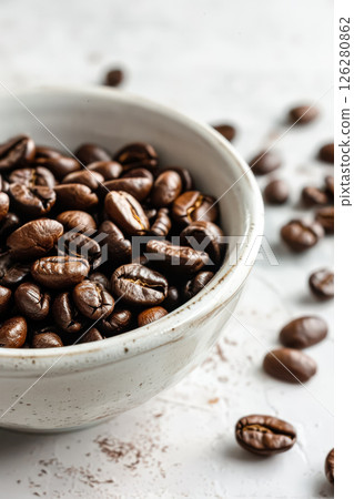 Bowl of coffee beans is on a white table 126280862