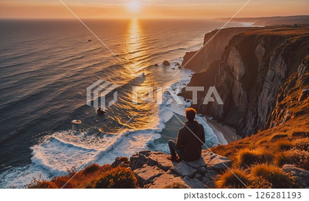 Man is sitting on a rock overlooking the ocean. The sky is orange and the sun is setting. The man is looking out at the water, taking in the beauty of the scene Man is sitting on a rock overlooking the ocean. The sky is orange and the sun is setting. The man is looking out at the water, taking in the beauty of the scene 126281193