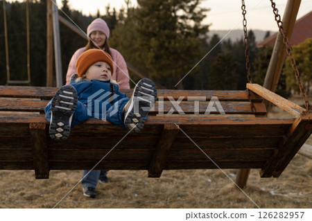 A woman swings her son on a swing 126282957