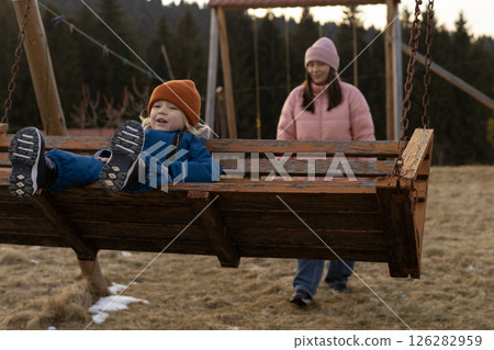 A woman swings her son on a swing in the yard 126282959