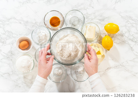 The image shows the ingredients for Lemon Spritz Cookies, including flour, sugar, butter, eggs, and fresh lemons, ready for baking. The image shows the ingredients for Lemon Spritz Cookies, including flour, sugar, butter, eggs, and fresh lemons, ready for baking. 126283238