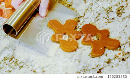 Using various festive cookie cutters, we're cutting out charming gingerbread cookies from the rolled dough on the sleek marble counter, bringing holiday cheer to the modern kitchen. 126283280