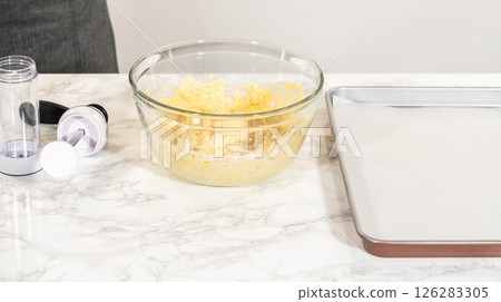 Lemon spritz cookies are neatly piped onto a baking sheet with a cookie press, ready for baking. The dough is shaped into beautiful little flowers, showcasing the precision and texture of the spritz Lemon spritz cookies are neatly piped onto a baking sheet with a cookie press, ready for baking. The dough is shaped into beautiful little flowers, showcasing the precision and texture of the spritz 126283305