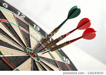Dartboard with three darts hitting bullseye center target. Precision, accuracy, skill, competition, pub games and recreational sports entertainment 126283635