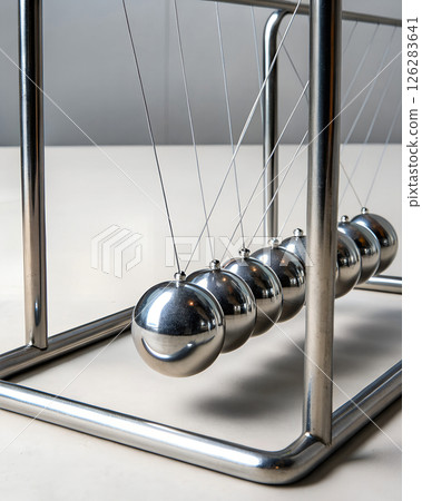 Newton's cradle pendulum physics demonstration device with chrome steel balls, momentum conservation and energy transfer in scientific education 126283641