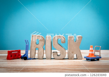 Risk Concept. Concrete alphabet letters on a light painted wood texture background 126283840
