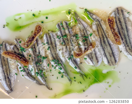 Fine dining presentation of marinated anchovies with vibrant garnish on a plate. Fine dining presentation of marinated anchovies with vibrant garnish on a plate. 126283850