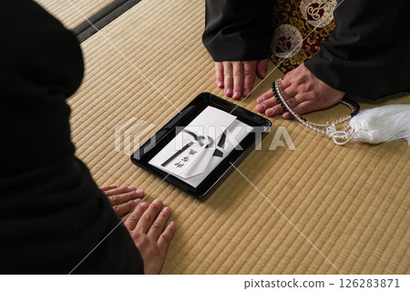 A scene of giving an offering to a monk at a memorial service 126283871