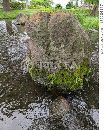 A large stone with moss floating on the water 126284127