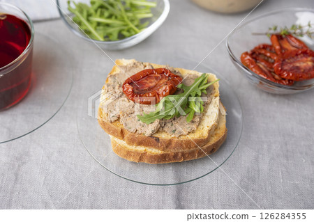 Chicken liver pate with wheat bread, arugula, sun-dried tomatoes and black tea. Homemade traditional rustic cuisine. Breakfast or snack option. Selective focus, close-up. 126284355