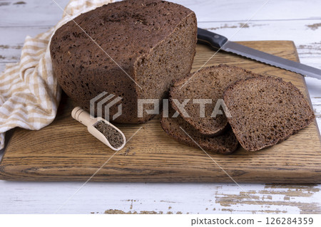 Rye Borodino (Borodinskiy) bread with a crispy crust on a wooden board, cut into slices. Homemade baking in rustic style. Selective focus, close-up. Rye Borodino (Borodinskiy) bread with a crispy crust on a wooden board, cut into slices. Homemade baking in rustic style. Selective focus, close-up. 126284359