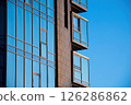 Modern Architectural Exterior highrise Building elegant Glass Facade. Sleek, Glasspaned windows contemporary design elements against clear blue sky, reflecting urban development stylish construction 126286862