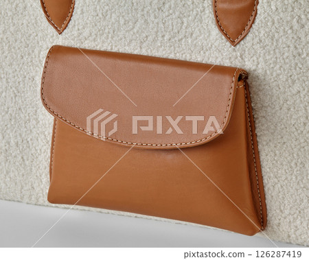 Stylish brown leather pocket detailing on a cozy cream-colored sherpa bag Stylish brown leather pocket detailing on a cozy cream-colored sherpa bag 126287419