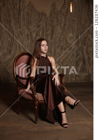 An Elegant Woman Gracefully Posing in a Stylish and Comfortable Chair, Showcasing Beauty 126287436