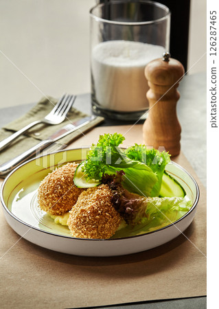 Breaded chicken kiev cutlets served on plate with mashed potatoes, fresh cucumber and lettuce Breaded chicken kiev cutlets served on plate with mashed potatoes, fresh cucumber and lettuce 126287465