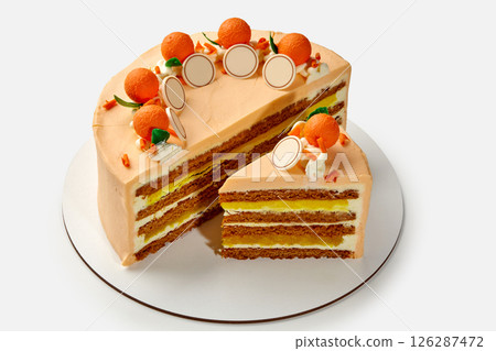 Delicious layered orange cake decorated with marzipan oranges and chocolate medallions on white background 126287472