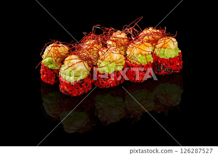 Delicious red sushi rolls topped with shrimp and guacamole with saffron reflecting on black background 126287527