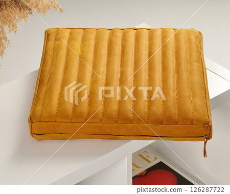 Mustard yellow leather laptop sleeve lying on white shelf 126287722