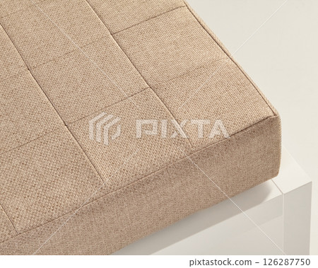 Beige upholstery fabric covering square tufted cushion on white furniture Beige upholstery fabric covering square tufted cushion on white furniture 126287750