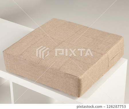 Beige fabric padded seat cushion resting on white shelf Beige fabric padded seat cushion resting on white shelf 126287753